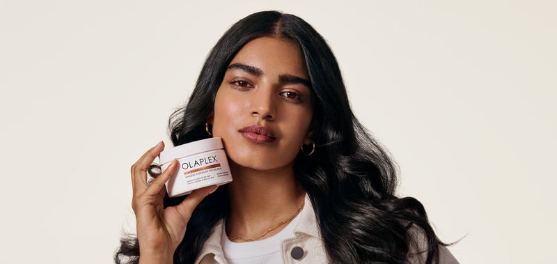 Women with long dark hair holding the OLAPLEX Rich Hydration Hair Mask 