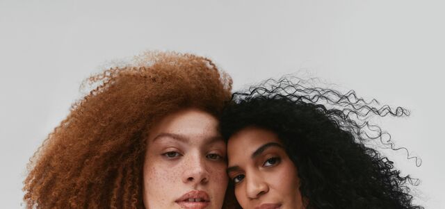 two women with curly hair on a blank background