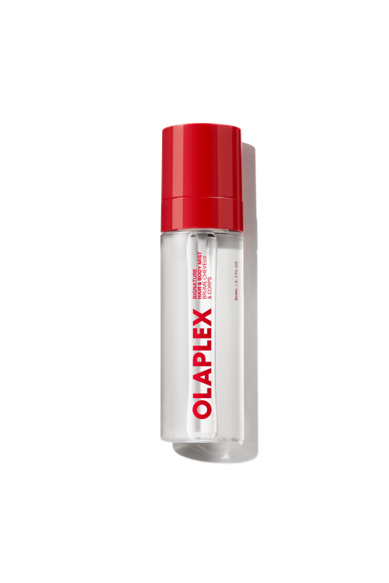 Un flacon transparent de brume parfumée pour les cheveux et le corps OLAPLEX avec un bouchon rouge vif et un logo OLAPLEX voyant imprimé verticalement sur le devant, présenté sur un fond de grille transparente. - main view
